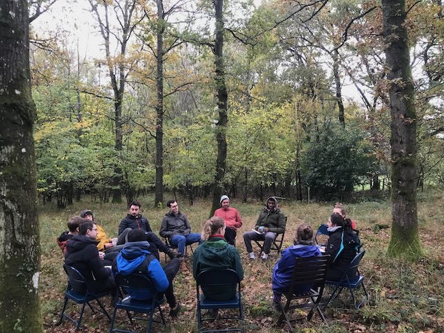 people gather in a circle in the wood
