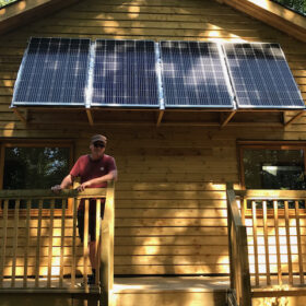 Photo showing a the Hideaway, a timber accommodation block at Hazel Hill Wood. It is powered by photovoltaics, which in this photo are seen fixed above the veranda