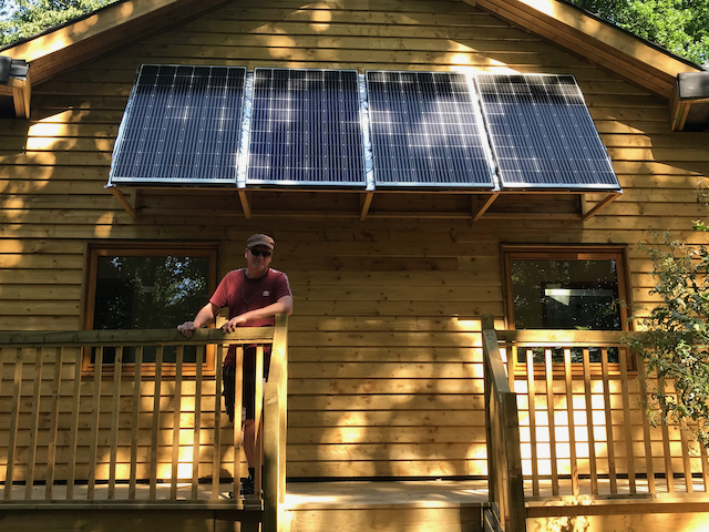 Photo showing a the Hideaway, a timber accommodation block at Hazel Hill Wood. It is powered by photovoltaics, which in this photo are seen fixed above the veranda