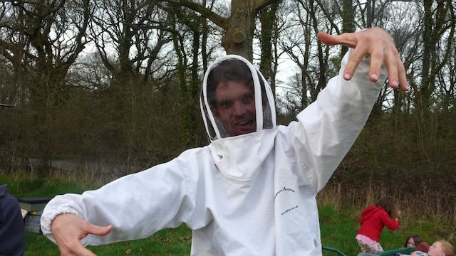 Oliver Broadbent in a beekeeping suit walking towards the camera like a zombie
